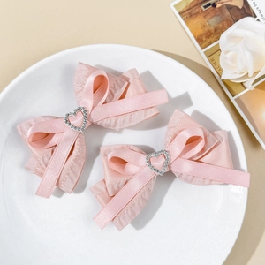 Paire de barrettes à cheveux avec nœud en satin rose et boucles en cristal en cœur