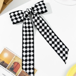 Pince à cheveux élégante avec nœud à damier noir et blanc et longs rubans sur fond blanc