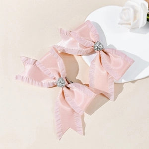 Dettagli di fiocchi per capelli in raso rosa con bordi arricciati e strass a cuore