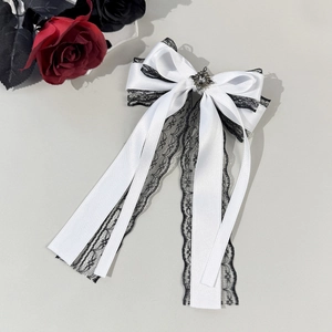Detail of gothic white satin bow hair clip with black lace trim and vintage diamond ornament