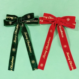 Detail of red and green velvet Christmas hair clips with gold Merry Christmas printing