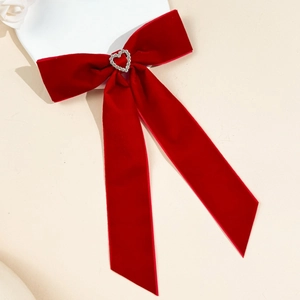 Détail d'une pince à cheveux en velours rouge avec strass en cœur et longs rubans élégants