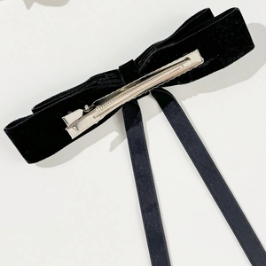Detail of the black velvet bow hair clip showing the silver metal alligator clamp on white