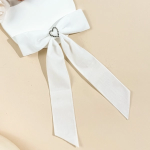 Gros plan d'un nœud en satin blanc avec un bouton en strass en forme de cœur étincelant
