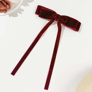 Close-up of luxury deep red velvet bow hair clip with long ribbons and elegant texture
