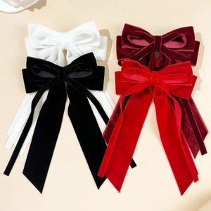 Flat lay view of velvet bow hair clips in black, white, red and wine colors with long streamers