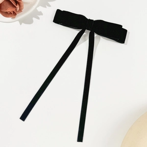 Detail view of the black velvet bow hair clip with long ribbons on a white background