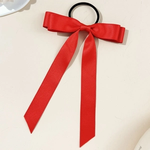 Detailed macro view of a large red satin bow hair tie with long ribbons on white background