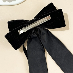 Detail of elegant black velvet bow hair clip showing the silver metal duckbill clip back