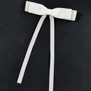 Detailed shot of white velvet bow hair clip with long ribbons on black background