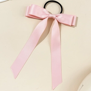 Close-up of pink satin ribbon bow hair tie with long streamers and elastic band