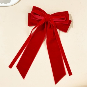 Close-up of deep red velvet bow hair clip with long elegant streamers and soft texture