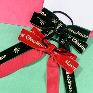 Close-up of velvet Christmas hair clips with gold Merry Christmas lettering and stars