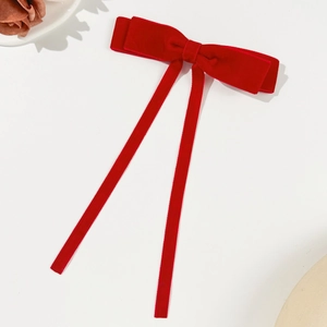 Close-up of elegant red velvet bow hair clip with long streamers and soft texture