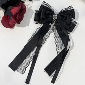 Detail of gothic black satin bow with lace, heart gemstone, and silver cross pendant