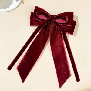 Close-up of elegant burgundy velvet bow hair clip with long streamers and soft texture