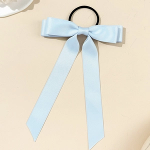 Detail of light blue ribbon bow hair tie with elegant long streamers and satin texture