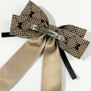 Macro shot of houndstooth bow hair clip with champagne gold satin ribbon and metal spring clip