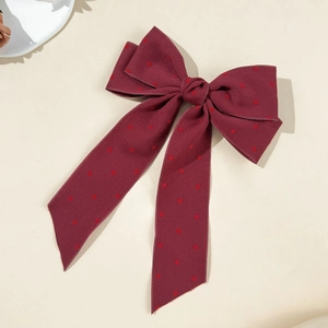 Detailed view of burgundy polka dot ribbon hair clip with elegant long streamers