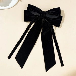 Close-up of elegant black velvet bow hair clip with long flowing ribbons and soft texture