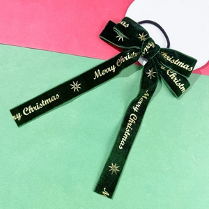 Detail of Christmas green velvet bow with golden Merry Christmas text and elastic hair tie