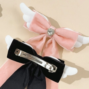 Detailansicht der rosa und schwarzen Schleifen-Haarspangen mit Flügeln und Entenschnabelclip