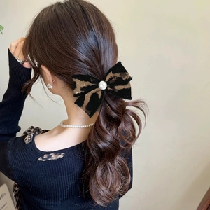 Detail of leopard print bow hair tie with pearl accent worn on ponytail