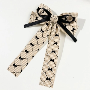 Elegant houndstooth bow hair clip with black silk ribbon on a clean white background