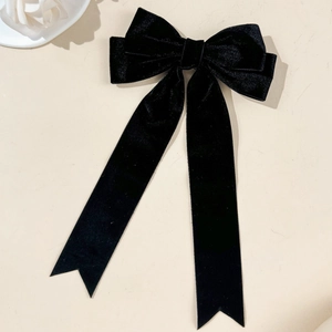 Detail of elegant black velvet bow hair clip with long ribbons on a minimalist background
