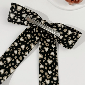 Macro view of leopard heart print fabric and silver metal hair clip attachment