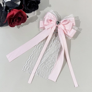 Detail of pink lace bow hair clip with black heart gem and hanging metal cross charm
