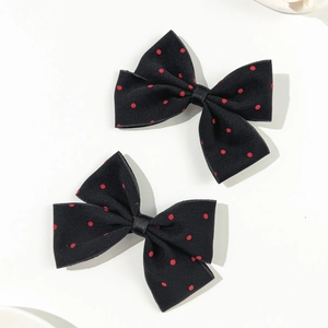 Close-up of two elegant black and red polka dot bow hair clips on white background