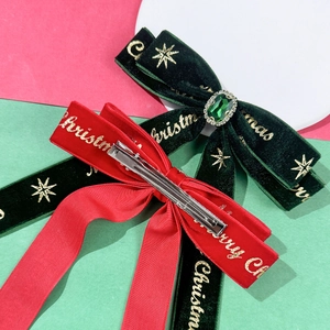 Close-up of velvet Christmas hair clips with emerald rhinestones and festive gold prints