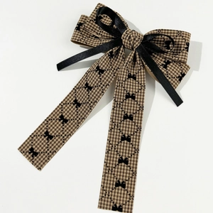 Detail of houndstooth bow hair clip with brown plaid patterns and black satin ribbons