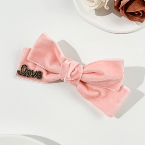 Detail showing pink velvet bow hair clip with black metal Love letter decoration