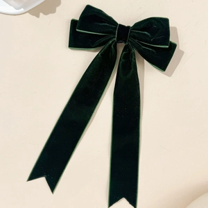 Close-up of dark green velvet bow hair clip with long ribbons and swallowtail ends