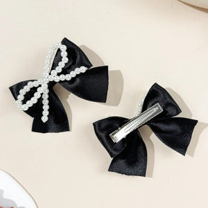 Détail de barrettes à nœuds en satin noir avec motifs en perles et pinces crocodiles en métal