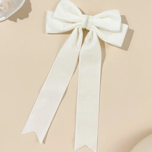 Detail of elegant cream velvet bow hair clip with long ribbons and swallowtail cut ends