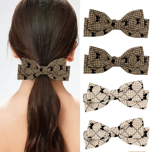 Détail des barrettes à cheveux à carreaux marron et kaki avec motifs papillon