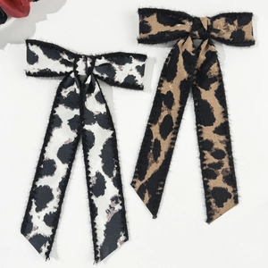 Detail view of stylish leopard print bow hair clips with long ribbons in brown and white