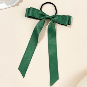 Detail of dark green satin bow hair tie with long ribbons and premium silk texture