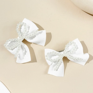Détail de pinces à cheveux en satin blanc avec bordure délicate en perles nacrées