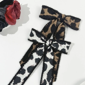Detail of leopard print bow hair clips with frayed edges in brown and grey color styles