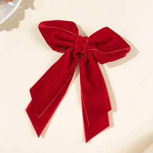 Detail view of a premium red velvet bow hair clip with elegant long trailing ribbons