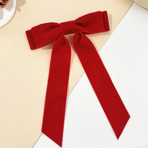 Macro detail of high-quality red velvet bow hairclip with long hanging ribbons