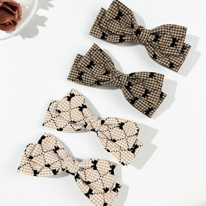 Détail de barrettes à nœuds à carreaux en marron et beige pour une coiffure de style anglais