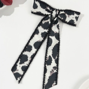 Detailed view of leopard print bow hair clip with long ribbons on white surface