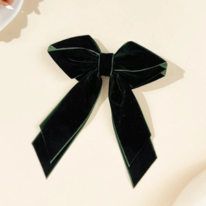 Detailed view of large dark green velvet bow hair clip with elegant long ribbons