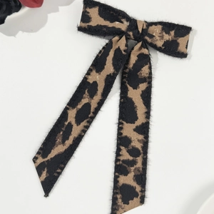 Close-up of leopard print bow hair clip with long ribbons and soft faux fur texture