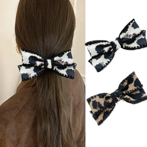 Detailed view of leopard print bow hair clips with plush trim on hair and flat lay